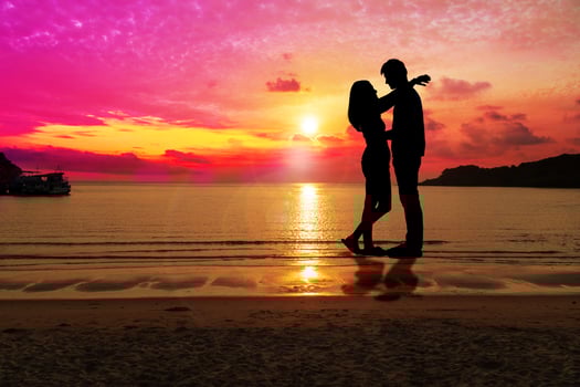 Silhouette happy young couple embracing each other with sunset at tropical beach with copy space. People standing on the beach with beautiful sky. Concept love and valentines day. photo
