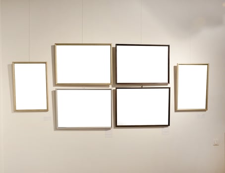 Blank picture frames on grey wall with glowing lamp, mock up photo