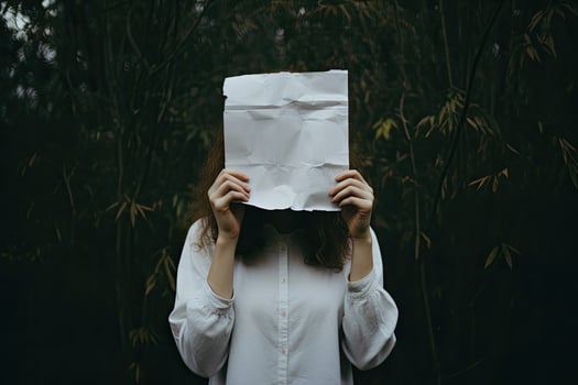 Woman covering her face with a sheet of paper in the forest. anonymous woman covering face with paper, AI Generated photo