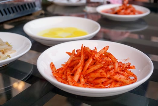 A Korean side dish made from papaya kimchi seasoning on a white round plate. photo