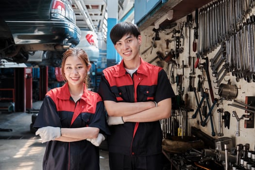 Portrait of two professional Asian mechanic partners smile and arms crossed with hand tools machinery, fixing work at car service garage, maintenance and repair jobs in automotive industry business. photo