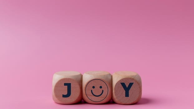 Word joy on wooden blocks with a smiling face symbol. Joy, happiness, pleasure, joyful emotion. photo