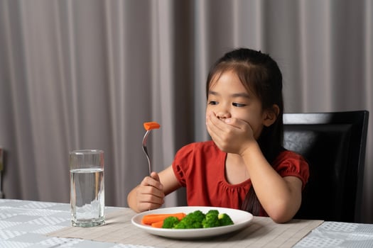 Little cute kid girl refusing to eat healthy vegetables. Children do not like to eat vegetables. photo