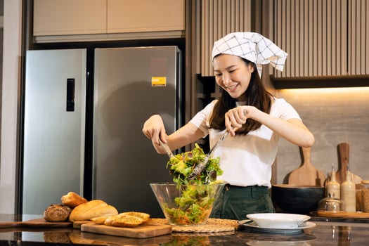 Asian housewife preparing fresh vegetables to make salad at home kitchen counter. photo