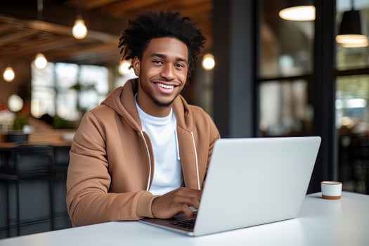 Portrait of Cheerful Black Male Student Learning Online in Coffee Shop, Young African American Man Studies with Laptop in Cafe, Doing Homework photo
