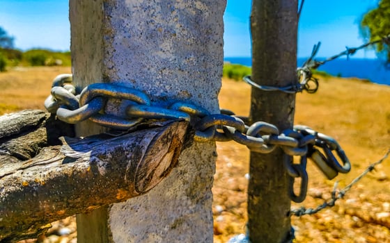 Nature beach and desert behind barbed wire fence and chains. photo