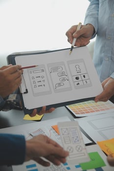 Close up ux developer and ui designer brainstorming about mobile app interface wireframe design on table with customer breif and color code at modern office.Creative digital development agency photo