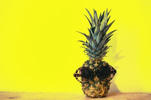 Pineapple with sunglasses on wooden table and yellow wall background. photo