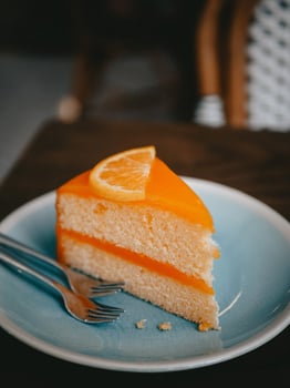 Orange cake with orange slice on blue plate in cafe, stock photo