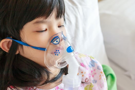 Sick little asian girl inhalation with nebulizer for respiratory treatment photo