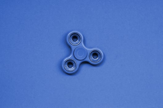Green fidget spinner lies on texture background of fashion pastel green color paper in minimal concept photo