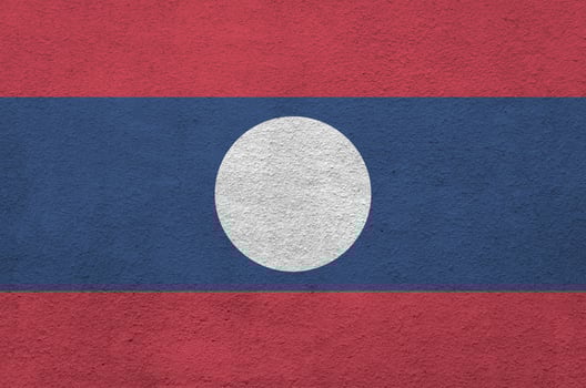 Laos flag depicted in bright paint colors on old relief plastering wall. Textured banner on rough background photo