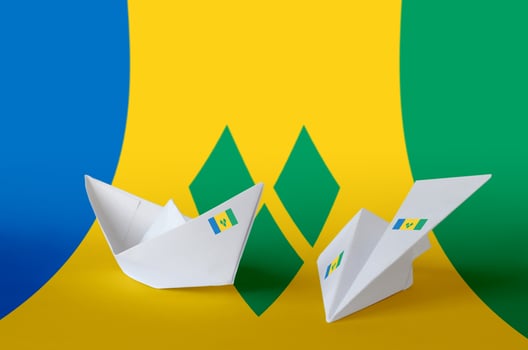 Saint Vincent and the Grenadines flag depicted on paper origami airplane and boat. Handmade arts concept photo