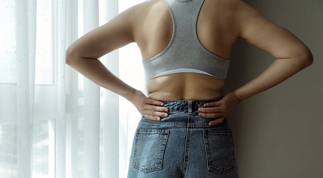 Close up of a belly with scar from c-section and abdominal fat. Women's health. A woman dressed up in sportswear demonstrating her imperfect body after a childbirth with nursery on the background. photo