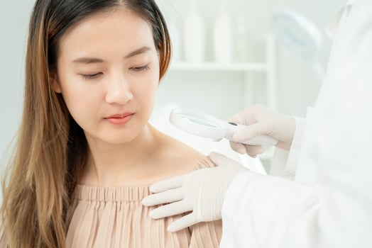 skin problem and beauty of asian girl. Dermatologist use magnifying glass look itchy skin from skin allergic, steroid allergy, sensitive skin, chemical allergy, rash, insect bites, Dermatitis. photo