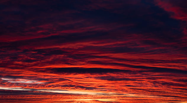 The dark red-orange sky is out of focus. Dramatic sky with dark clouds. Sunset. Banner. Noise. photo