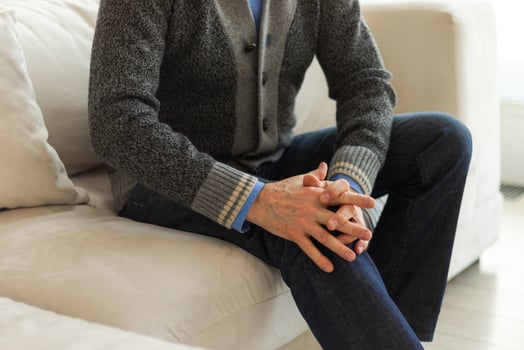 Knee pain arthritis body sick health care concept. Middle aged senior man suffering from knee ache sitting on sofa at home. Mature old senior grandfather hands touching leg feeling pain hurt in knee. photo