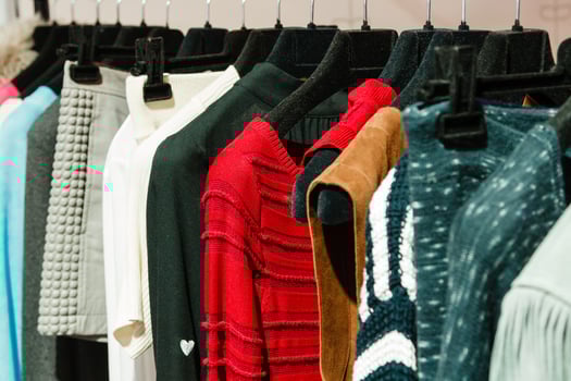 outerwear on hangers, sweaters, skirts, blouses photo