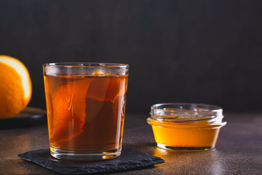 Hard alcoholic brown butter cocktail with orange zest in a glass photo