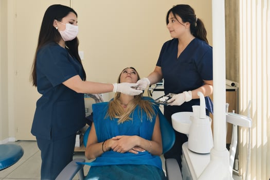Female dentist with a help of her assistant fixing teeth of a woman patient in the dentists chair. photo