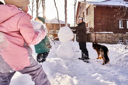 A family builds a snowman out of white snow in the yard in winter. photo