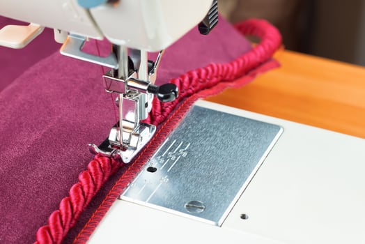 sewing machine. the process of sewing a decorative cord of red fabric. photo