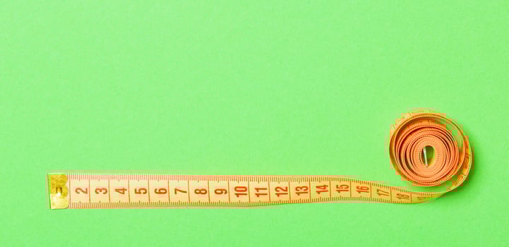 Frame made of measuring tape on green background. Top view of sewing concept. Slim waist concept with empty space for your design photo