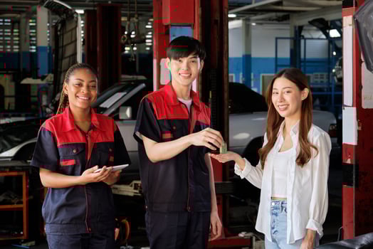 Asian female customer receives car key from automotive staff workers, quality guarantee with trust at maintenance garage, professional vehicle service center, ensuring fix checks, and repair industry. photo