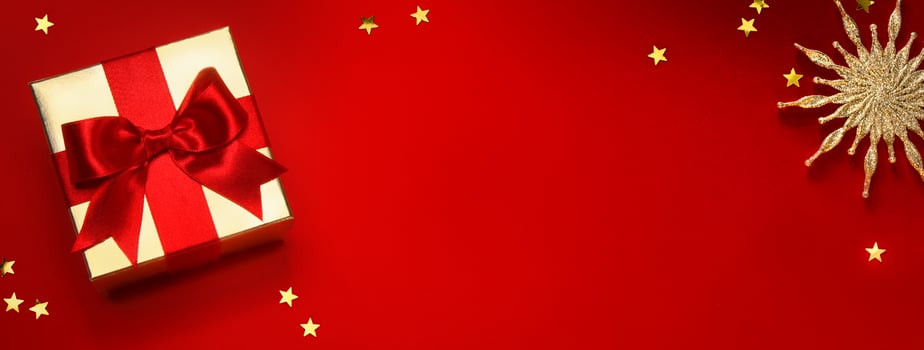 Christmas banner or greeting card background with christmas gift box and golden decoration on red background photo