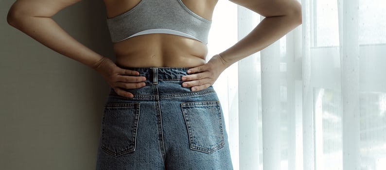 Close up of a belly with scar from c-section and abdominal fat. Women's health. A woman dressed up in sportswear demonstrating her imperfect body after a childbirth with nursery on the background. photo