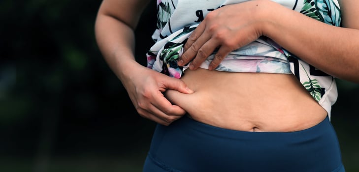 Women body fat belly. Obese woman hand holding excessive belly fat. diet lifestyle concept to reduce belly and shape up healthy stomach muscle. photo
