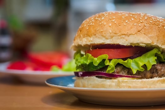Homemade burger with tomato and beef patty, fresh toppings on whole grain artisan bun on kitchen table for dinner photo