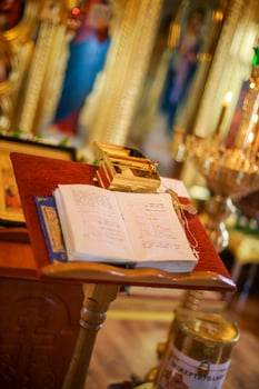 Open bible lying on the altar at the king's gate in the church. The box with things for anointing the child during the christening of the Orthodox church. Soft focus Defocused photo