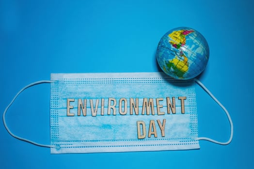 Word ENVIRONMENT DAY of wooden letters against background of protective medical mask. globe model Earth on blue background. Environmental protection concept. photo