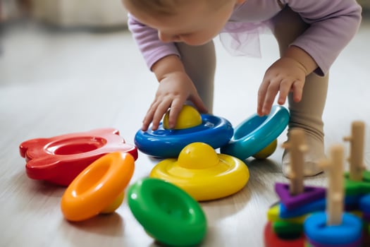 little kid sorting colorful rings on pyramid. child plays with toys on floor in room. Child development after one year. photo
