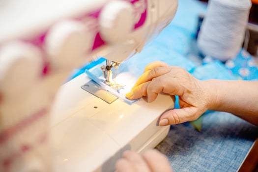 Sewing Homemade protective medical mask in process. woman holds a spunbond, sms, Meltblown mask at home. Detail White modern sewing machine and three-layer masks. photo