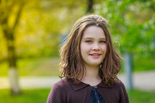 Beautiful girl among cherry flowers in spring. Portrait of a girl with brown hair and green eyes. photo