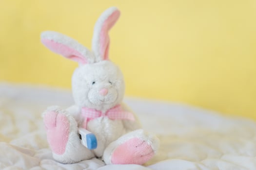Toy Hare with electronic thermometer under paw. Measuring high temperature of children with influenza and viruses, coronavirus. Medicine concept. photo