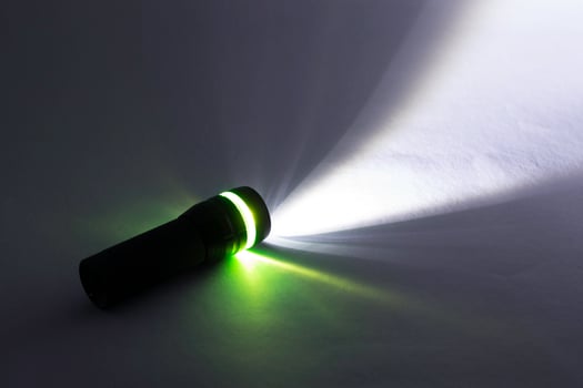 black flashlight lighting up shines green and white ray light beam torch. object emergency electric tool energy lamp lantern led battery power for security search or direction view finding in dark. photo