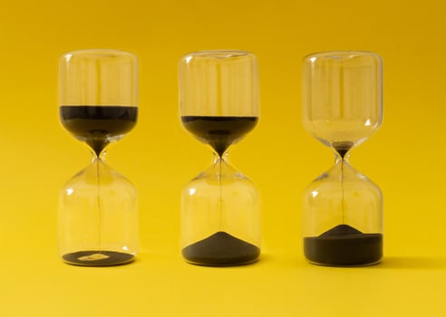 Like sands through the hourglass, so are the days of our lives. Creative hourglass, sandglass, sand timer or sand clock against yellow background concept. Minimal background idea. Hourglass aesthetic. photo