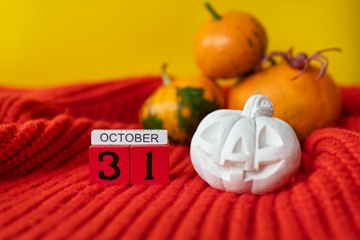 Against the background of a pumpkin with a painted face, a spider, a plaster figure, a wooden calendar on a red sweater. Holiday concept of October 31, Halloween. photo