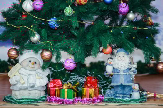 Santa and Snowmen under the tree. Christmas lights on the tree. photo
