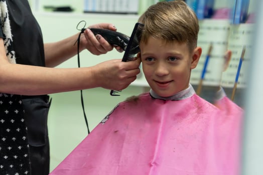 Hair cutting for a child using a hair clipper in a beauty salon photo