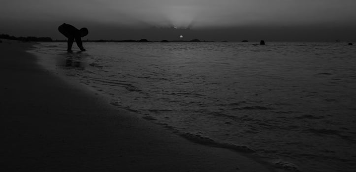 Silhouette of people touching the sea in a Black and White view photo