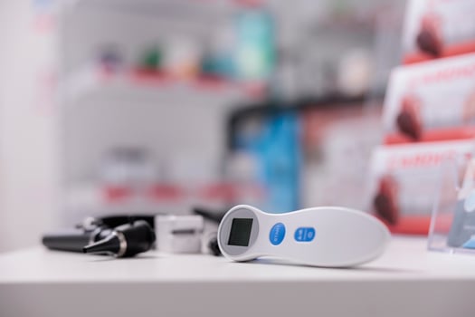 Medical thermometer standing on table in empty drugstore, health care instruments ready to be used by professional. Pharmacy equipped with pharmaceutical products, vitamins and supplements photo