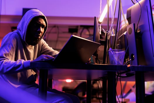 Scammer tricking victims online to steal personal information and money. African american criminal planning cyberattack and coding malicious software on laptop to breach data photo