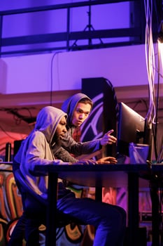 Criminals hacking computer system together and programming malware for password cracking. Man checking malicious software code on hacker computer and helping to break into database photo