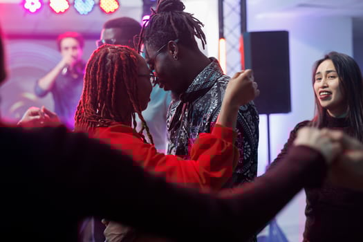 Young couple in love dancing together and hugging in crowded nightclub. African american man and woman embracing while moving and showing affection on dancefloor surrounded with clubbers photo
