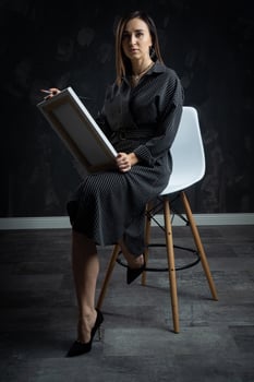 a young brunette female artist stands behind an easel. photo
