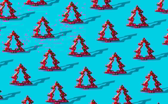 Minimal composition pattern background of red Christmas trees on light blue. New Year or Christmas concept. Trendy winter holidays pattern background idea. photo